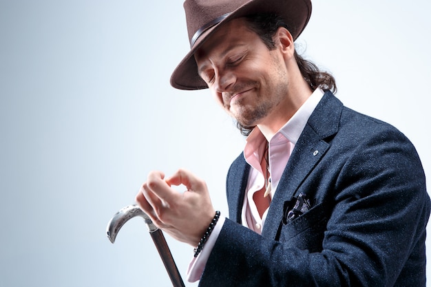 Free Photo the mature bearded man in a suit and hat holding cane. isolated on a gray.