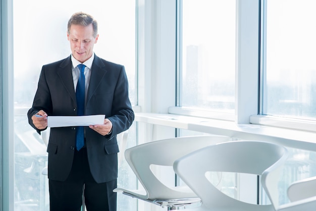 Free Photo mature businessman examining document in office