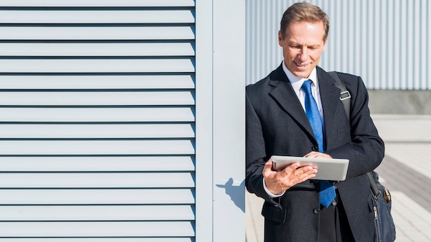 Free photo mature businessman using digital tablet at outdoors