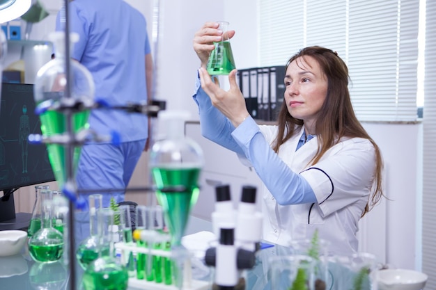 Free photo mature female scientist making scientific test in her research lab. chemical test tubes.