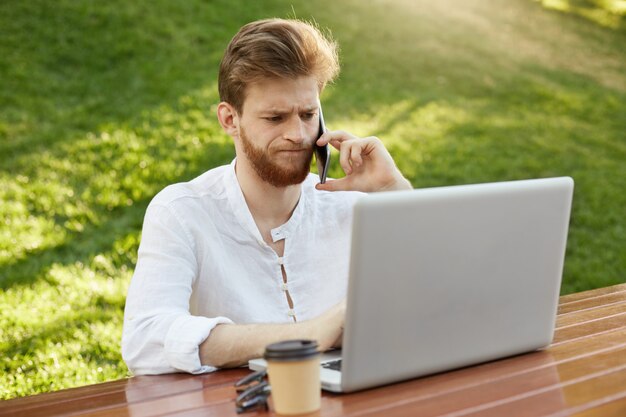 Mature ginger handsome man with laptop computer in the park