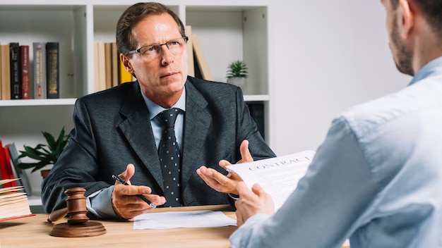 Free photo mature lawyer discussing contract with client in the courtroom