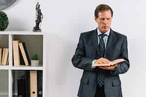 Free photo mature lawyer reading law book in the office