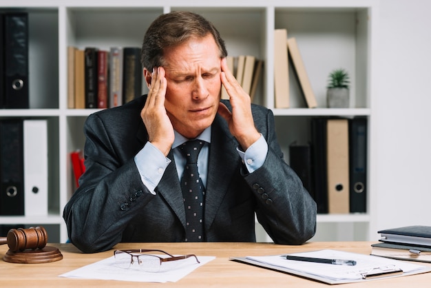 Mature lawyer with headache sitting in the courtroom