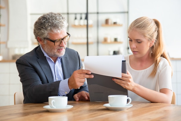 Free Photo mature legal advisor reading document and explaining details to young customer