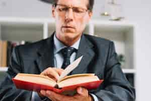 Free photo mature male judge reading book in courtroom