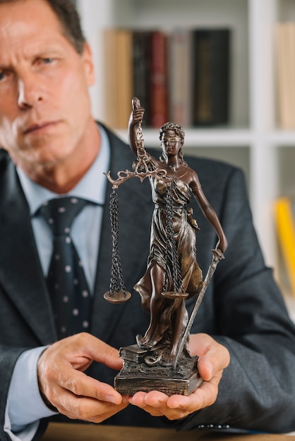 Free photo mature male lawyer holding statue of justice in hand