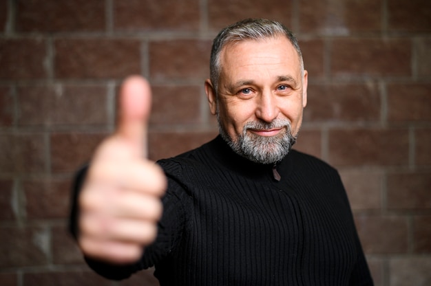 Mature man posing next to blurred brick wall