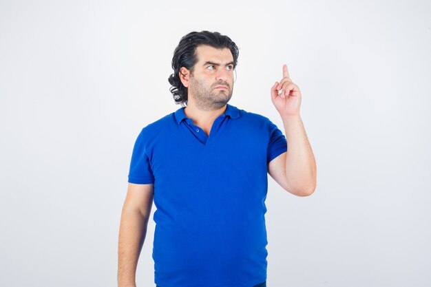 Mature man raising index finger in eureka gesture in blue t-shirt