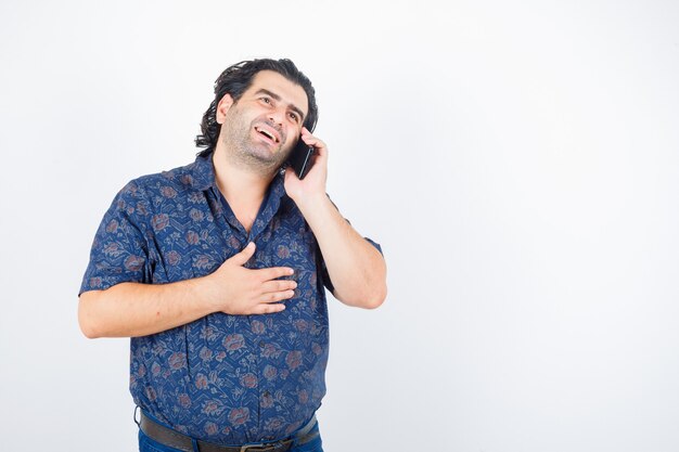 Mature man talking on mobile phone in shirt and looking happy. front view.