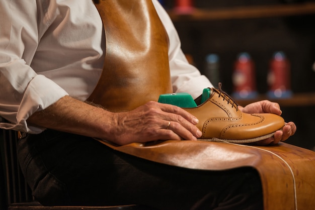 Mature shoemaker in workshop making shoes