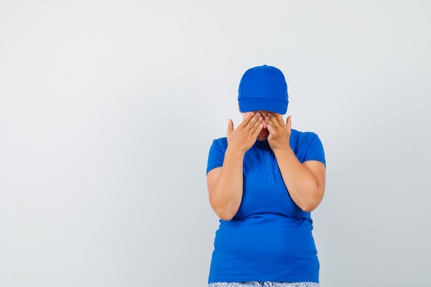 Free photo mature woman covering eyes with hands in blue t-shirt and looking amused.