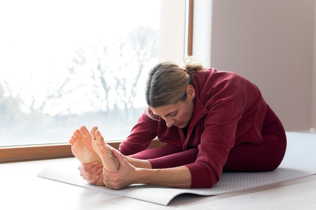 Mature woman doing sport exercises next to her window