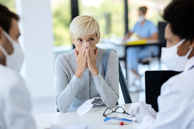 Free photo mature woman feeling worried while having appointment at doctor's office during coronavirus epidemic