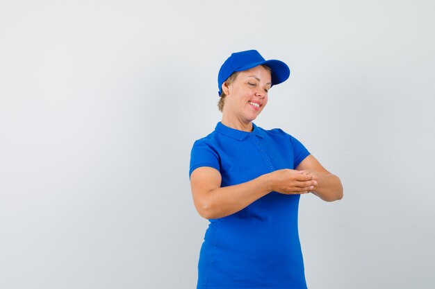 Mature woman looking at her fingers in blue t-shirt and looking peaceful.