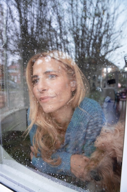 Free photo mature woman looking outside her window while it rains