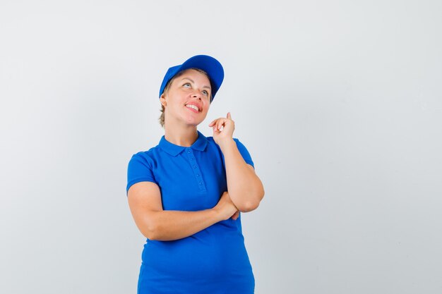 Mature woman looking up with finger up in blue t-shirt and looking hopeful