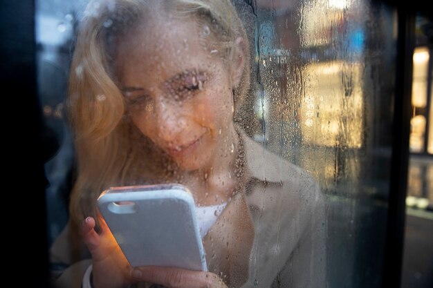 Mature woman texting on the phone while it rains