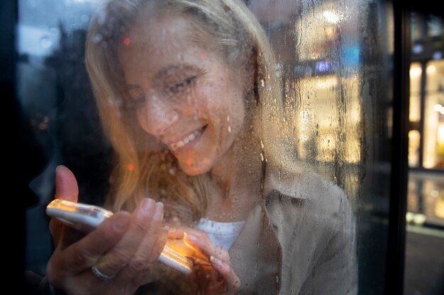 Mature woman texting on the phone while it rains