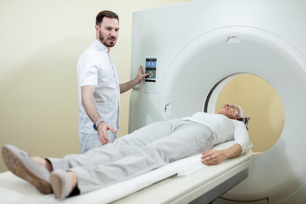 Free photo mature woman undergoing for ct scanning while medical technician is supervising the procedure in the hospital