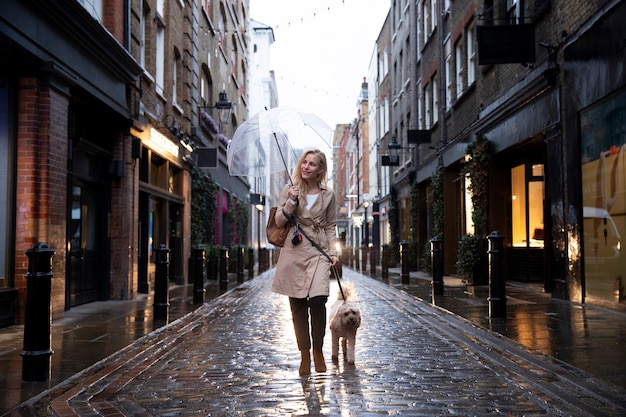 Free Photo mature woman walking her dog while it rains