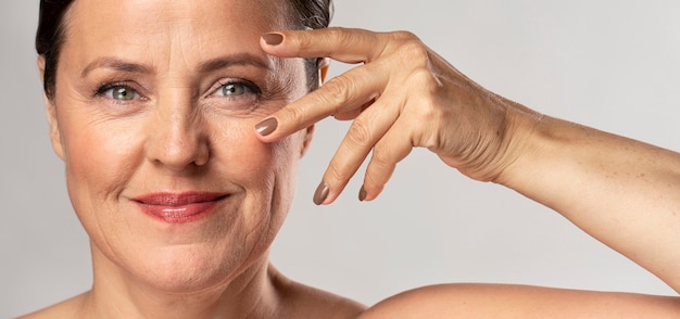 Free Photo mature woman with make-up on posing with hand on face and showing off nails