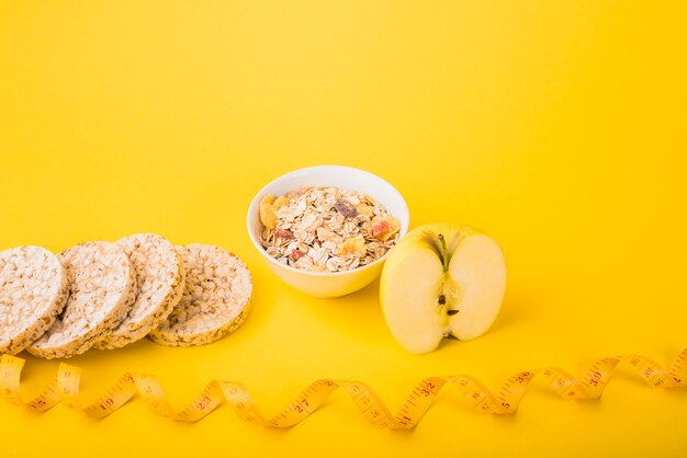 Measuring tape near fruit, crisp bread and bowl of muesli