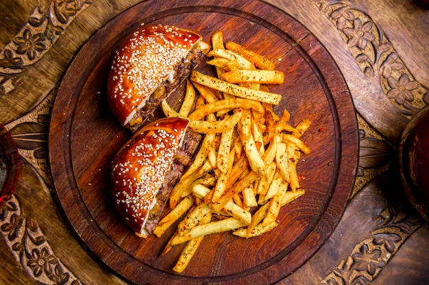 Meat burger on wooden board french fries top view