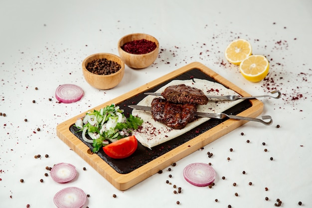 Free photo meat kebab on chompur with onions on a wooden board