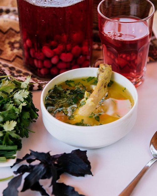 Free photo meat piece inside broth soup with herbs and a glass of red berry composto.