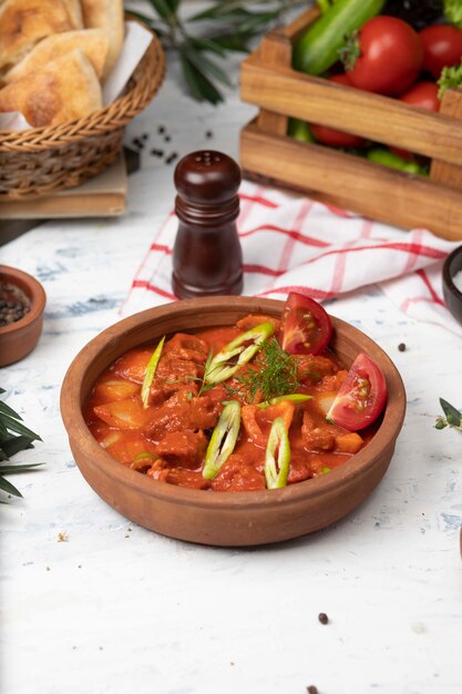 Meat potato stew with tomato sauce and pepper in pottery bowl. 