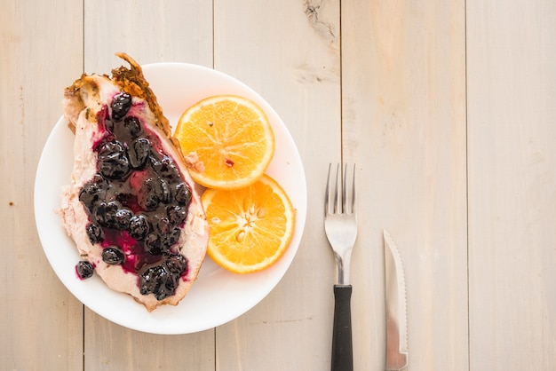 Meat with jam near oranges on plate