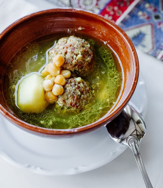 meatball soup in broth with potatoes, beans and herbs.