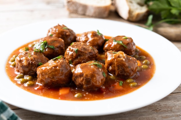 Free photo meatballs green peas and carrot with tomato sauce on wooden table