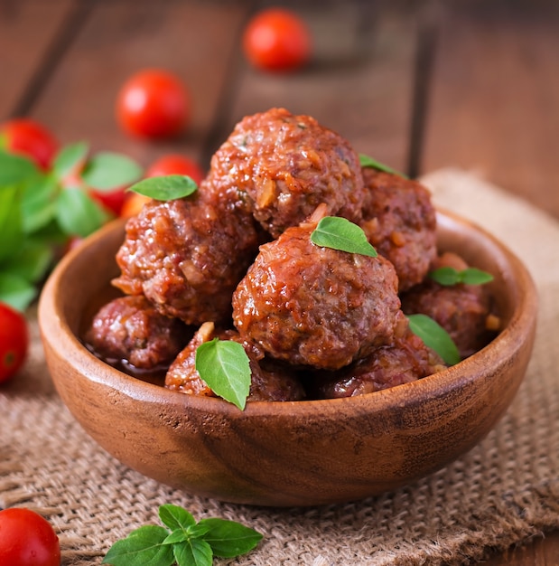 Free Photo meatballs in sweet and sour tomato sauce and basil in a wooden bowl