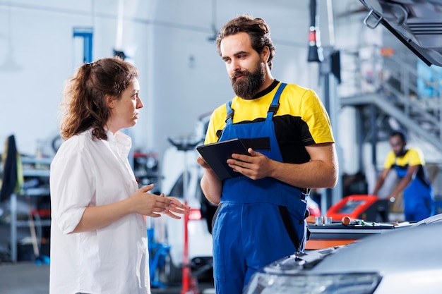 Free Photo mechanic in car service ordering new lights system for damaged vehicle using tablet worker next to client looking online for components to replace old ones in malfunctioning automobile