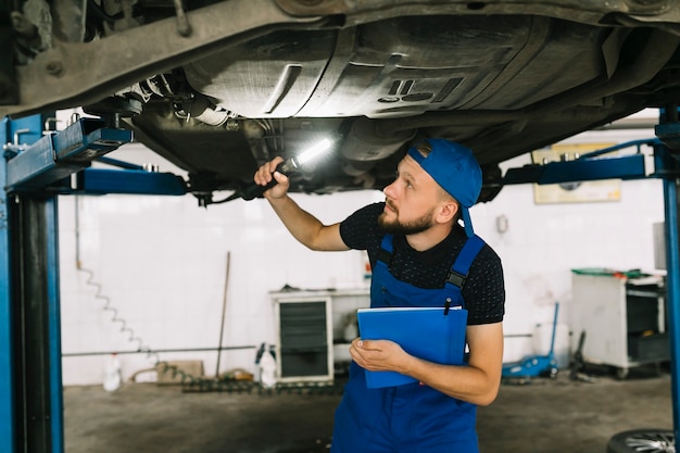 Free Photo mechanic checking bottom of car