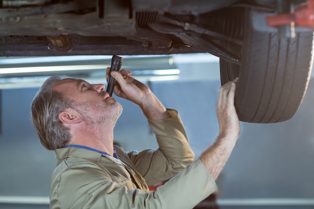 Free Photo mechanic examining car using flashlight