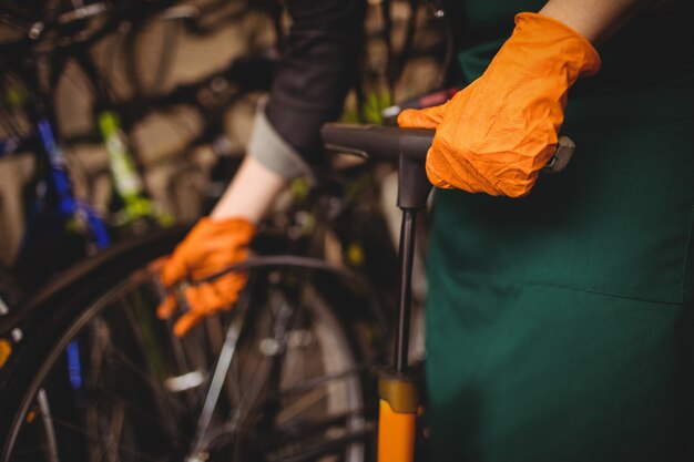 Mechanic filling air into bicycle tire with air pump