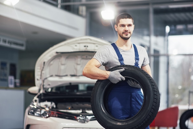 Free photo mechanic holding a tire tire at the repair garage. replacement of winter and summer tires