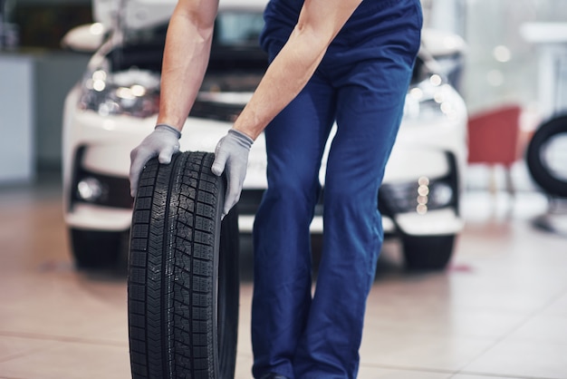 Mechanic holding a tire tire at the repair garage. replacement of winter and summer tires