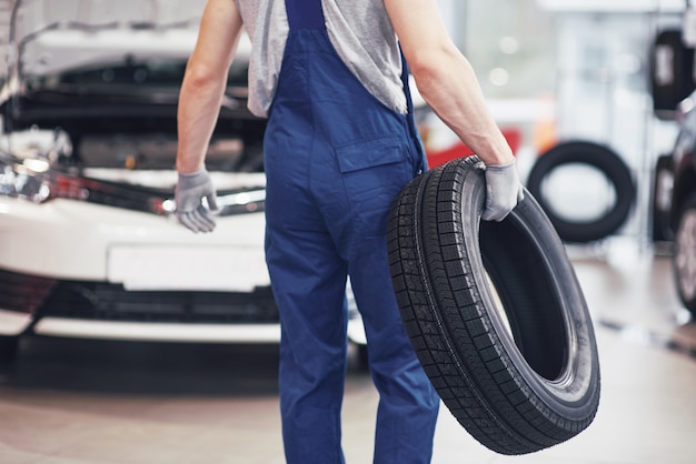 Mechanic holding a tire tire at the repair garage. replacement of winter and summer tires