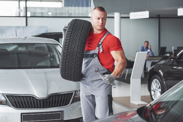 Free photo mechanic holding a tire tire at the repair garage. replacement of winter and summer tires.