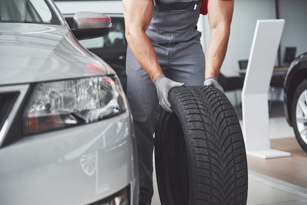 Mechanic holding a tire tire at the repair garage. replacement of winter and summer tires.