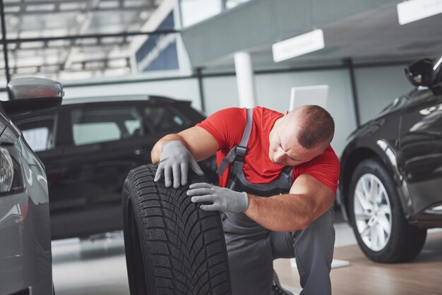 Free Photo mechanic holding a tire tire at the repair garage. replacement of winter and summer tires.