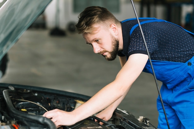 Free photo mechanic repairing car motor