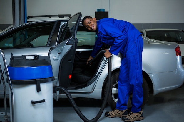 Free photo mechanic servicing car with vacuum cleaner