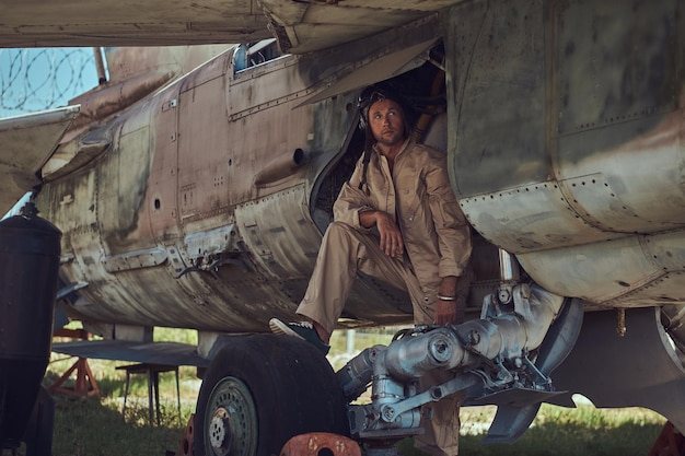 Free Photo mechanic in uniform and flight helmet carries out maintenance of an old military bomber in the open air museum.