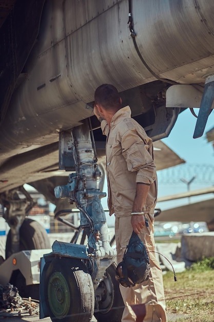 Free Photo mechanic in uniform standing near a war fighter-interceptor in an open-air museum.