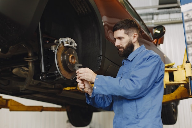 Mechanic with a tool. Wheel in hands of a mechanic. Blue work clothes.